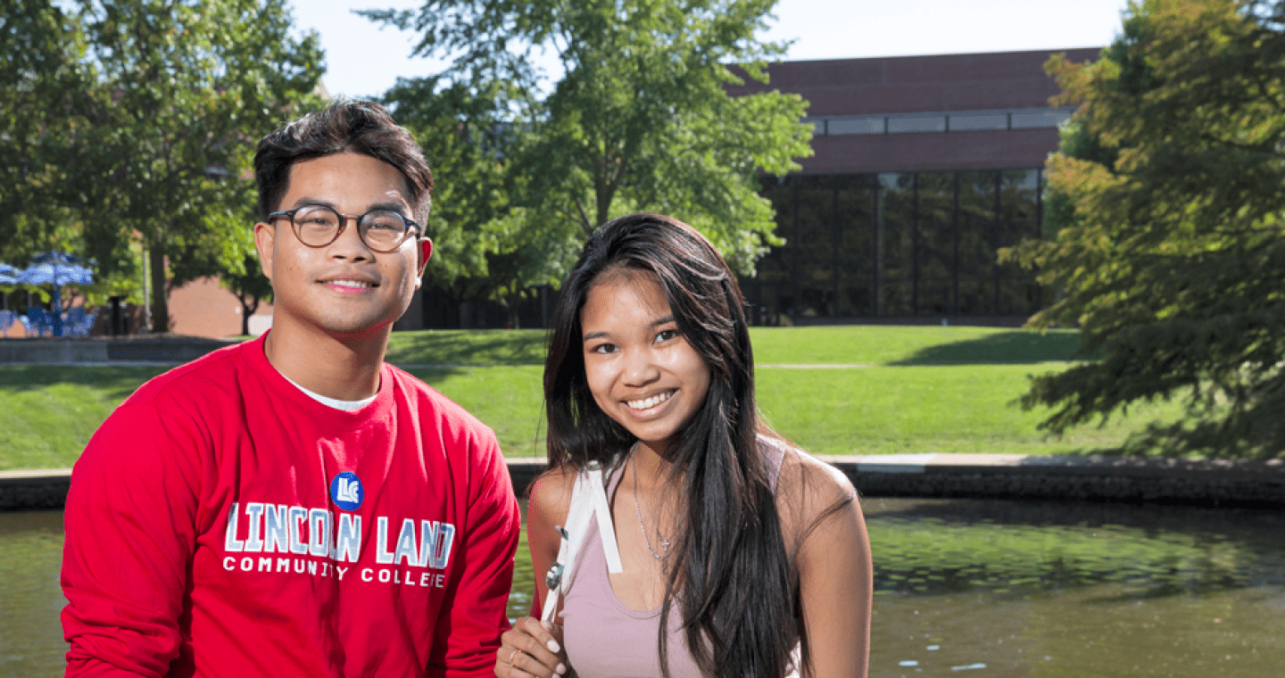 Two 绿帽社 students by lake on campus
